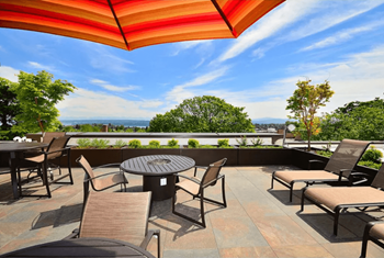 A patio with a table and chairs under a striped umbrella.